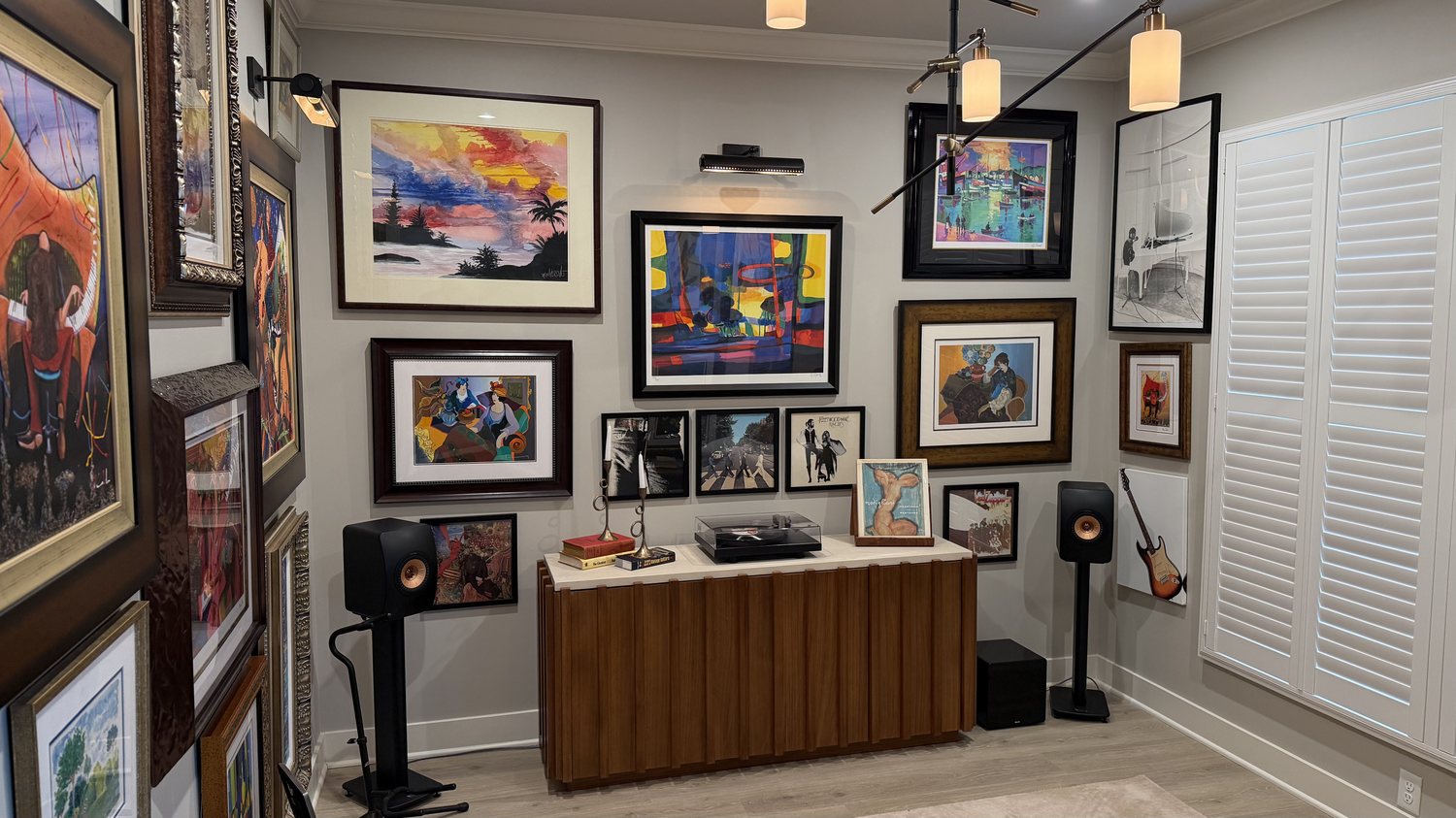 Media room after, with a turntable console, bookshelf speakers and a floor to ceiling art collection