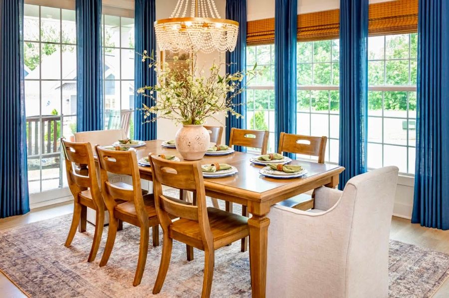 Dining room with a beaded chandelier, blue drapery and a set table