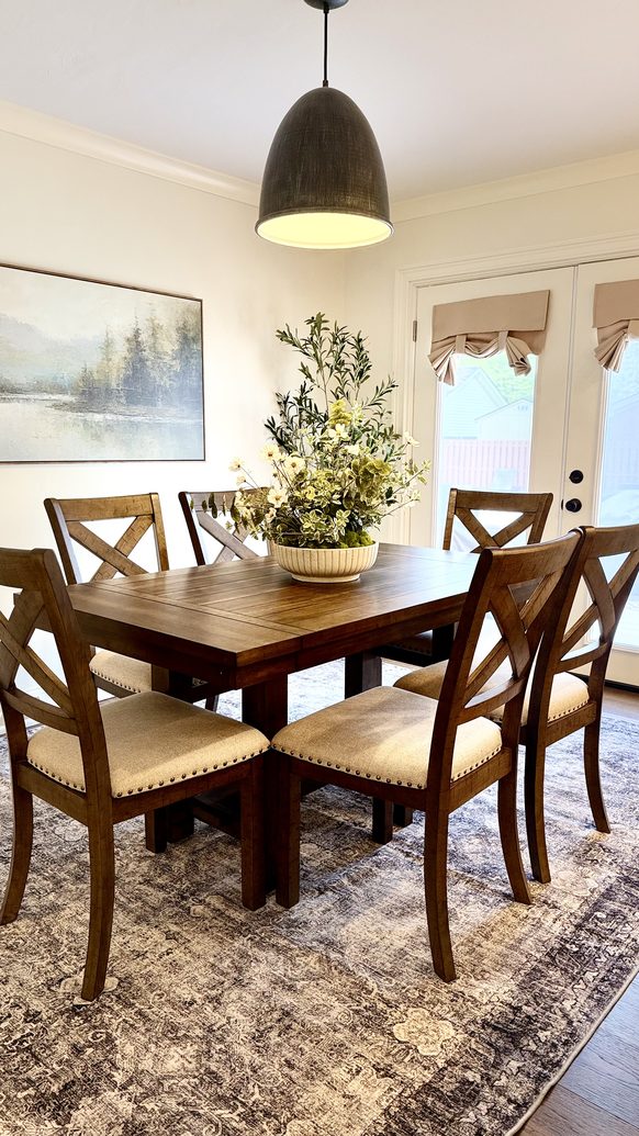 Dining room with a trestle table, cane back chairs and a framed landscape
