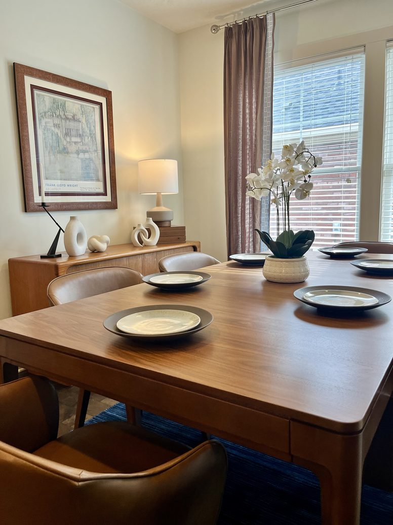 Dining room with a walnut table, leather chairs and layered place settings