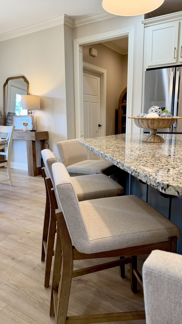 Granite topped bar seating with upholstered stools open to the kitchen