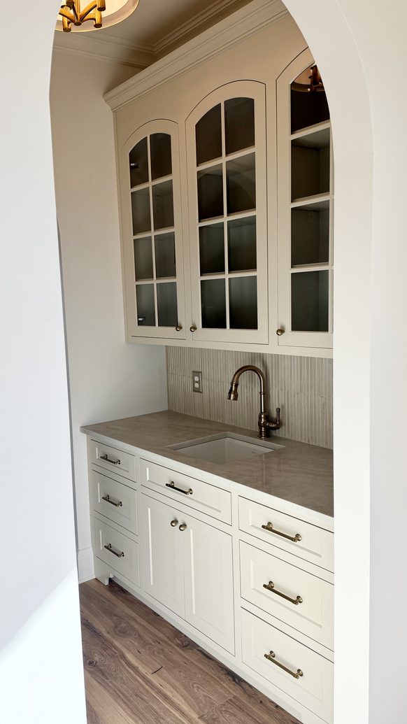 Butler's pantry with glass front cabinetry, a prep sink and brass fixtures