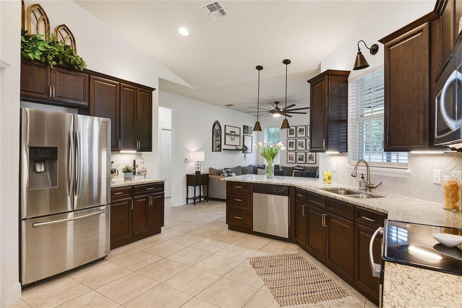 Kitchen with dark cabinetry, a peninsula island and stainless appliances