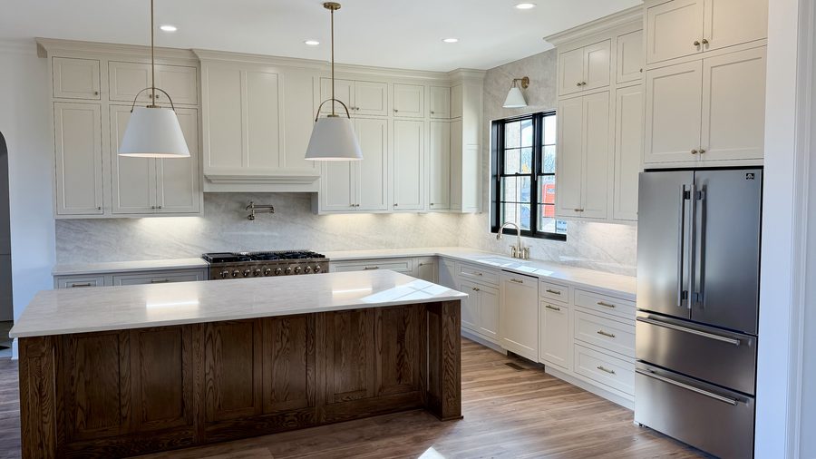 White kitchen with a dark stained island and marble countertops