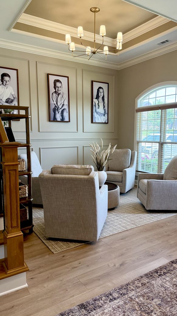 Library seating area with panelled walls, portrait art and a brass chandelier
