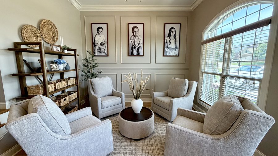 Panelled sitting room with a shelving wall, four swivel chairs and family portraits
