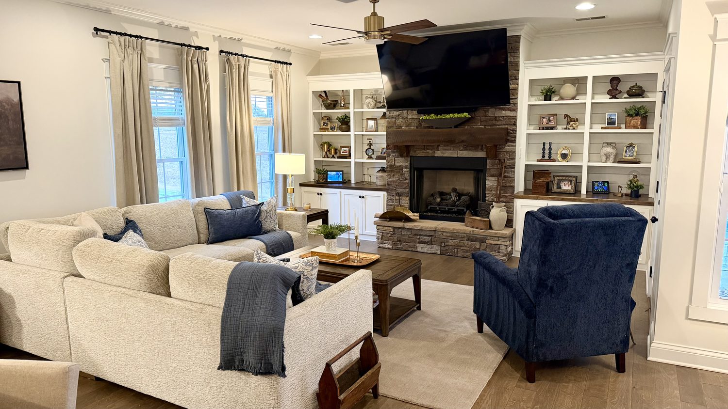 Living room with a stone fireplace, custom built-ins and a neutral sectional