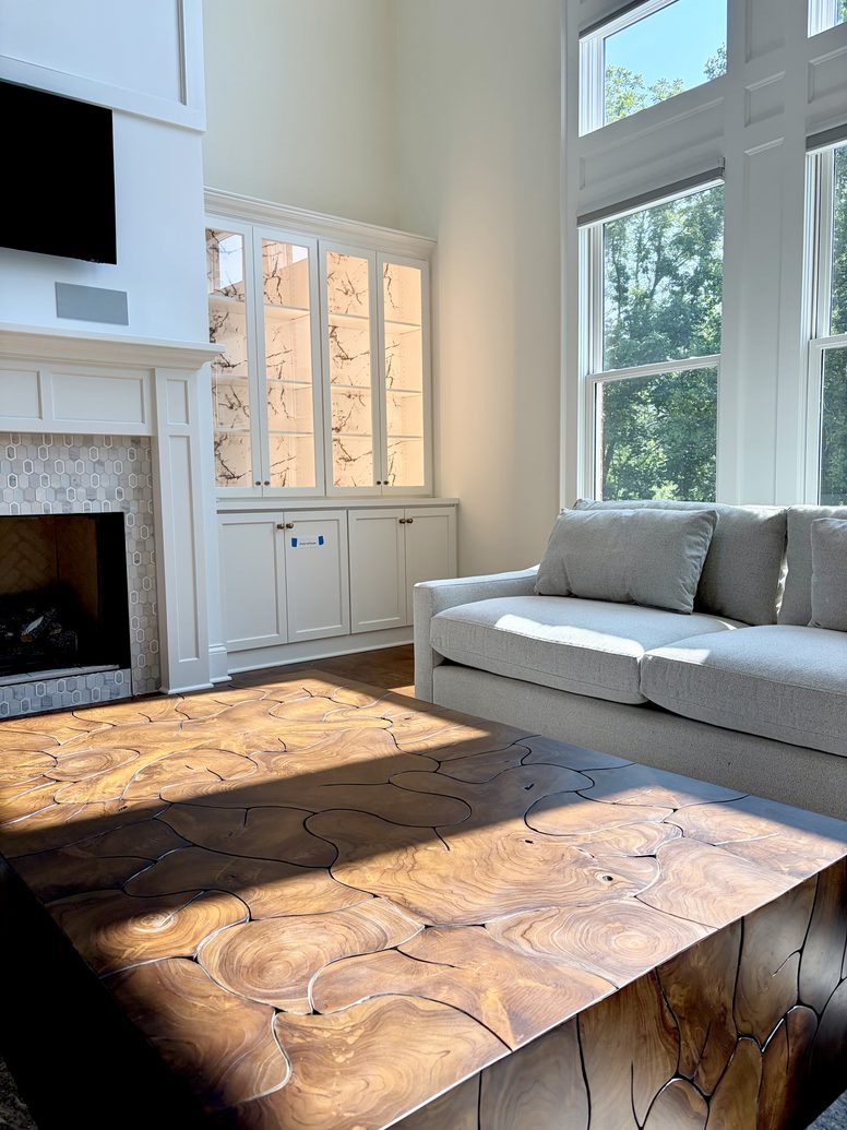 Live edge walnut table in a living room with a fireplace and tall windows
