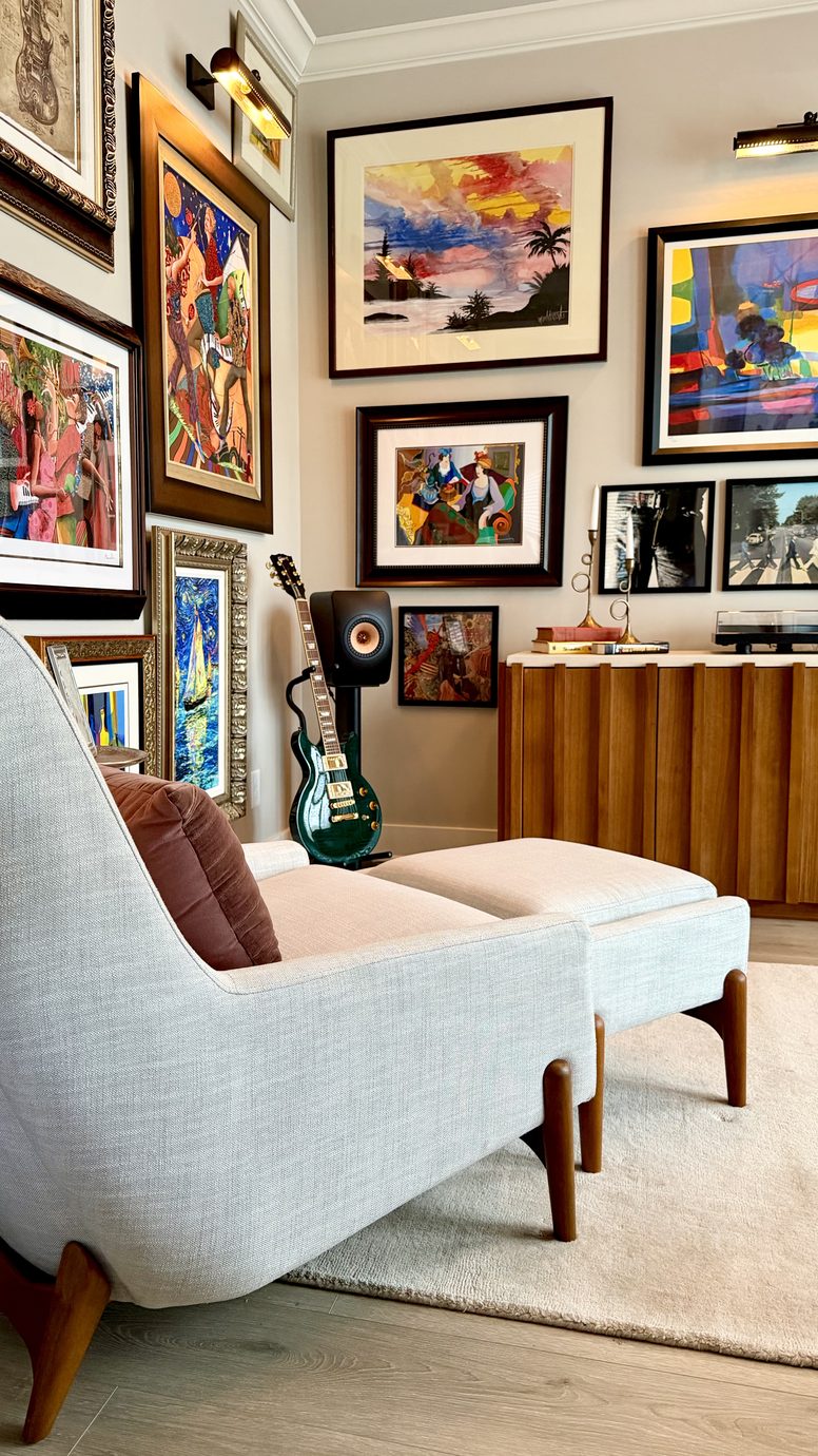 Music room with a gallery wall of art, guitars on display and a pair of armchairs