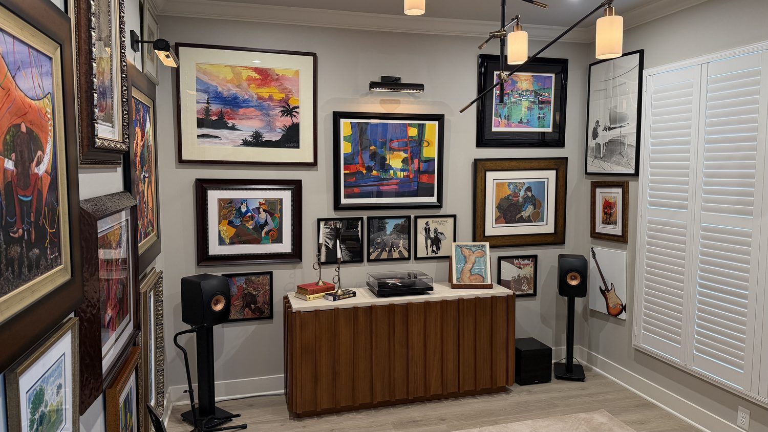 Music room with a turntable console, bookshelf speakers, electric guitar and a floor to ceiling art collection