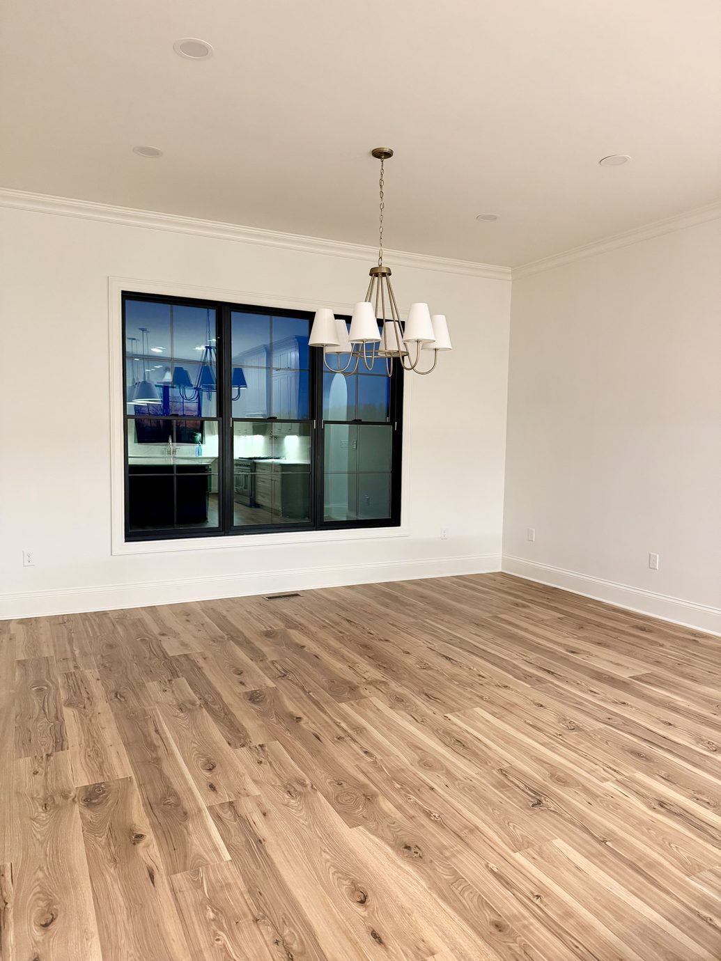 New construction dining room with a black iron chandelier and white oak floors