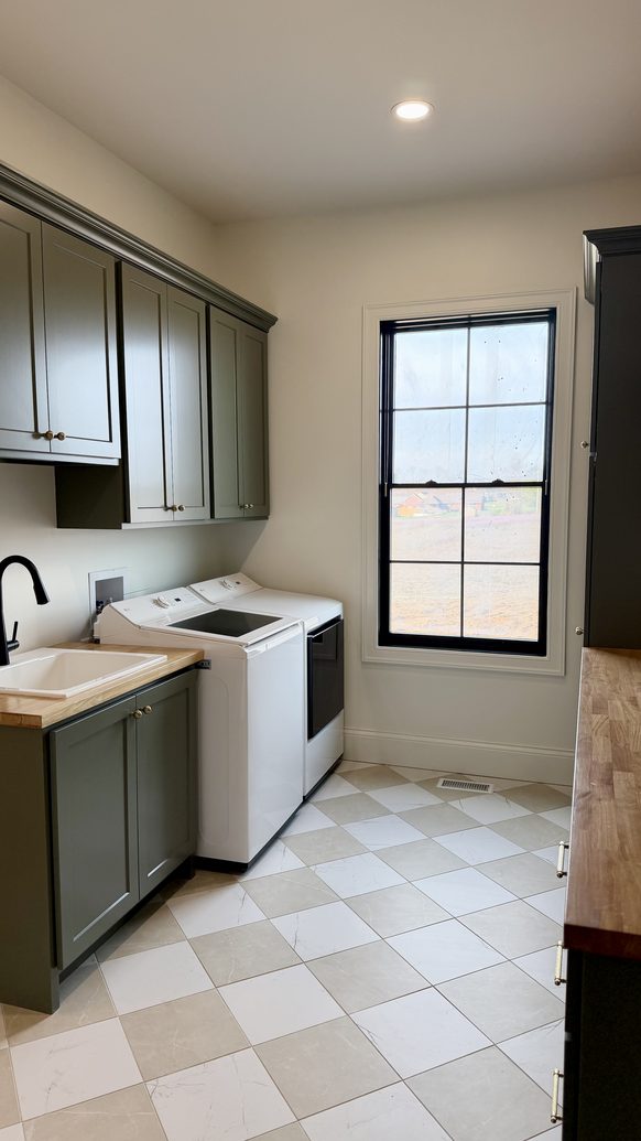 Laundry room with green cabinetry, a utility sink and chequerboard tile floor