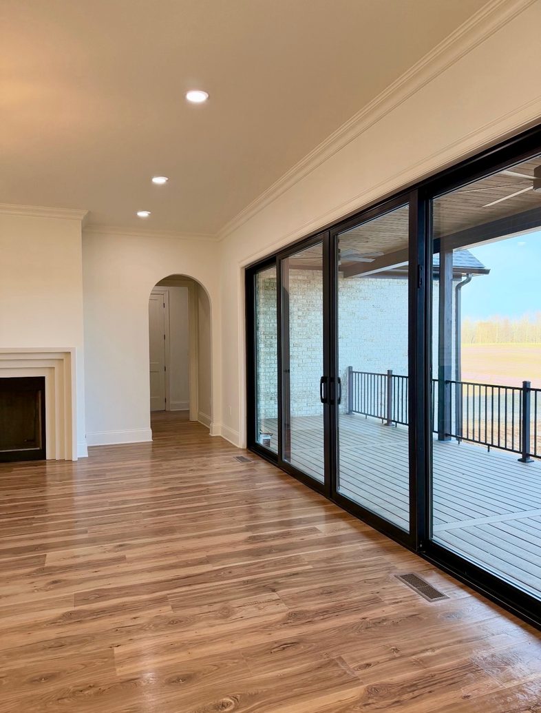 New construction living room opening to a covered deck through sliding glass doors