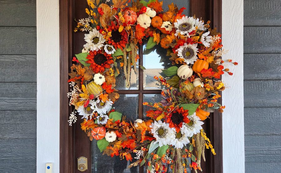 Autumn wreath of sunflowers, pumpkins and berries on a front door
