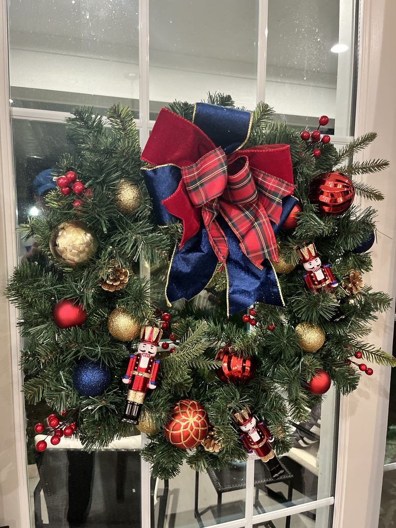 Christmas wreath with nutcrackers, tartan ribbon and gold ornaments on a glass door