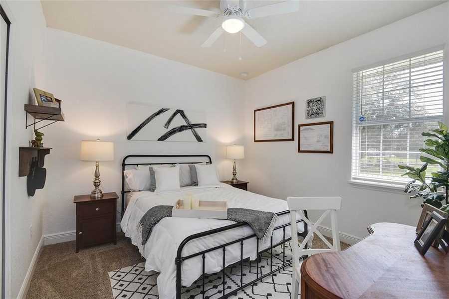 Guest bedroom with a black iron bed, striped bedding and framed art