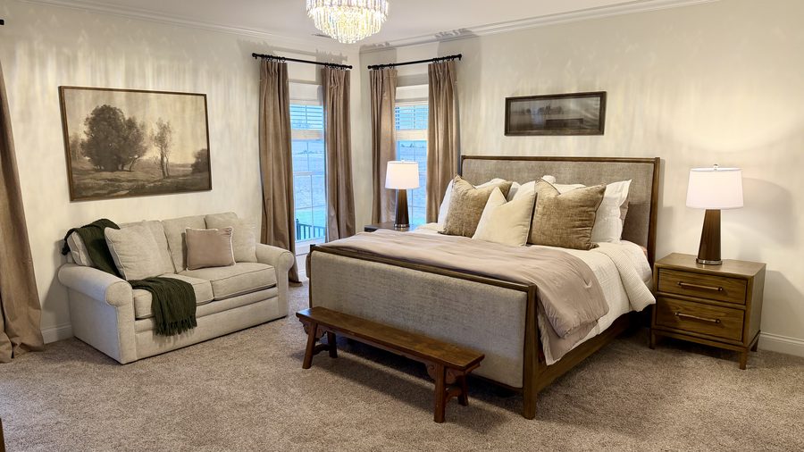 Primary bedroom with a crystal chandelier, upholstered bed and seating area