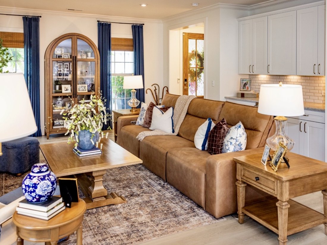 Living room with a caramel leather sofa, blue drapery and an arched display cabinet
