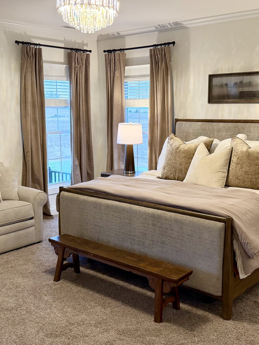 Primary bedroom with a crystal chandelier, upholstered bed and a seating area
