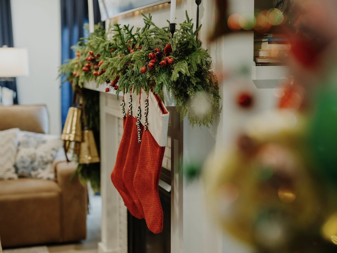 Christmas mantel with cedar garland, red berries and knit stockings above a lit fireplace